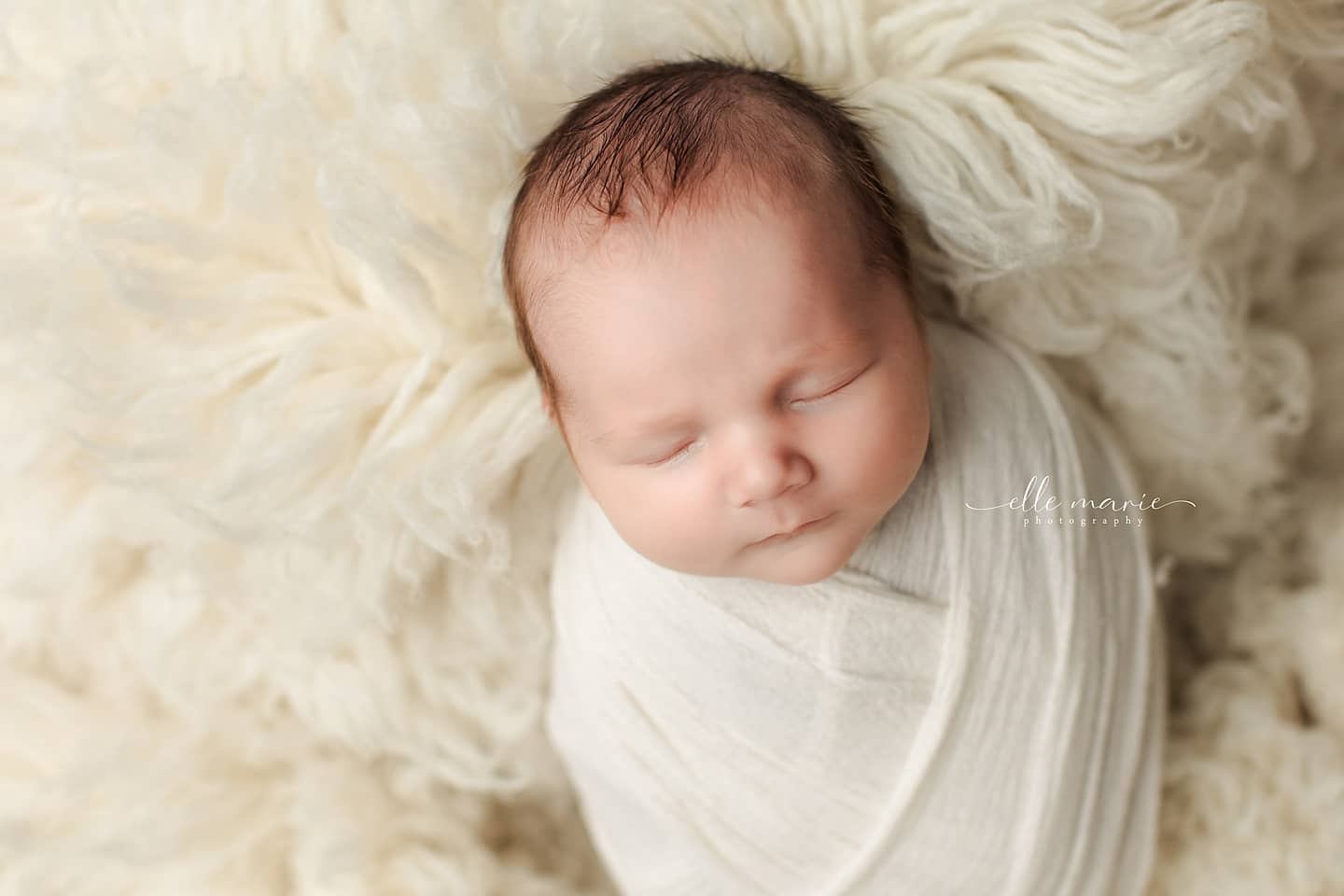 newborn baby wrapped in off white swaddle