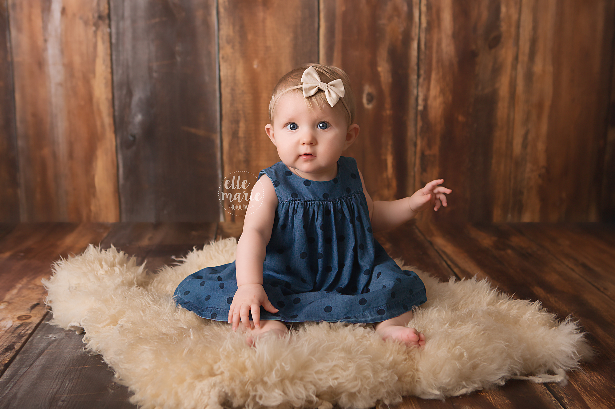6 month sitting on fur looking at camera