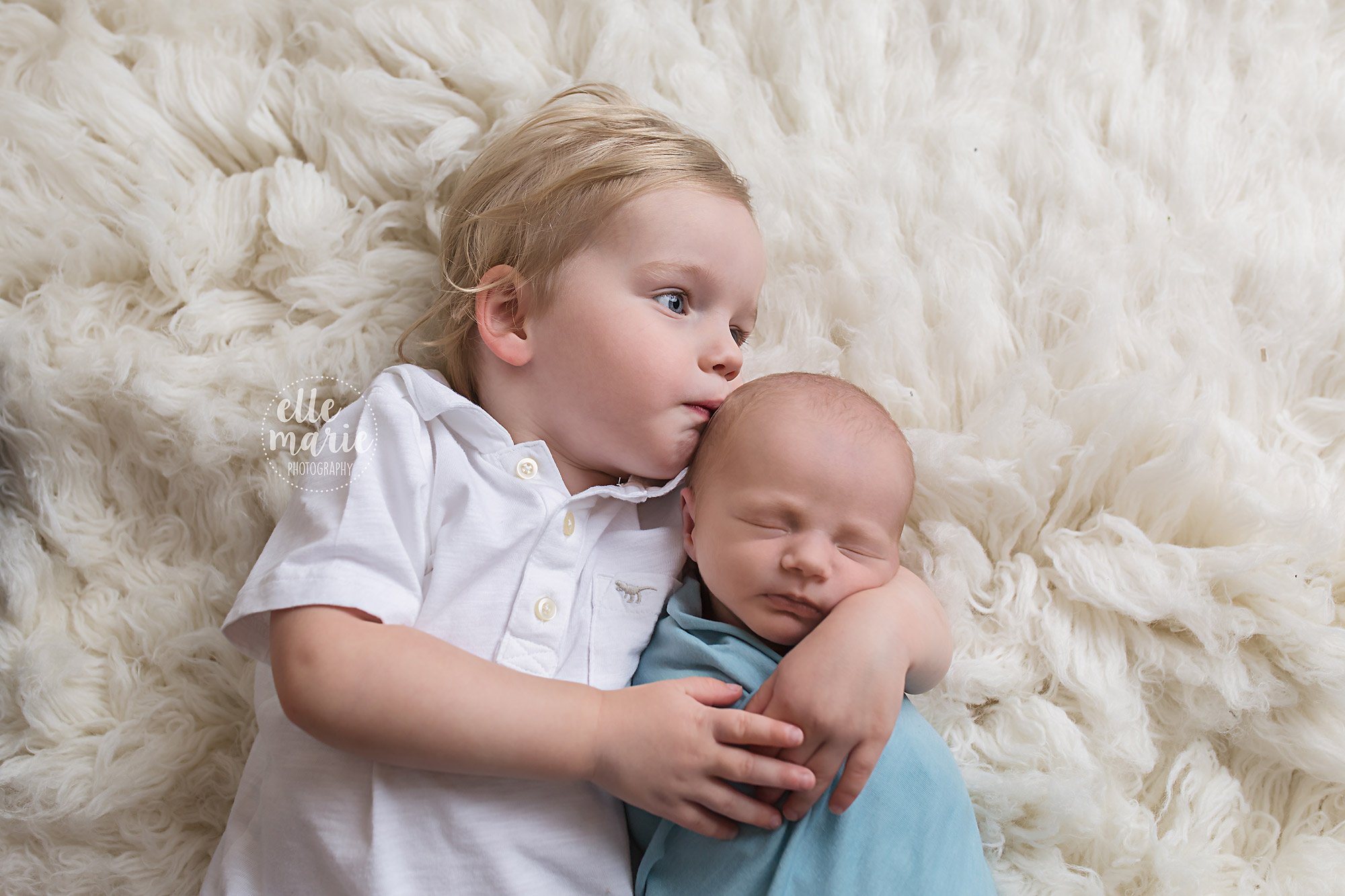 toddler kissing newborn brother