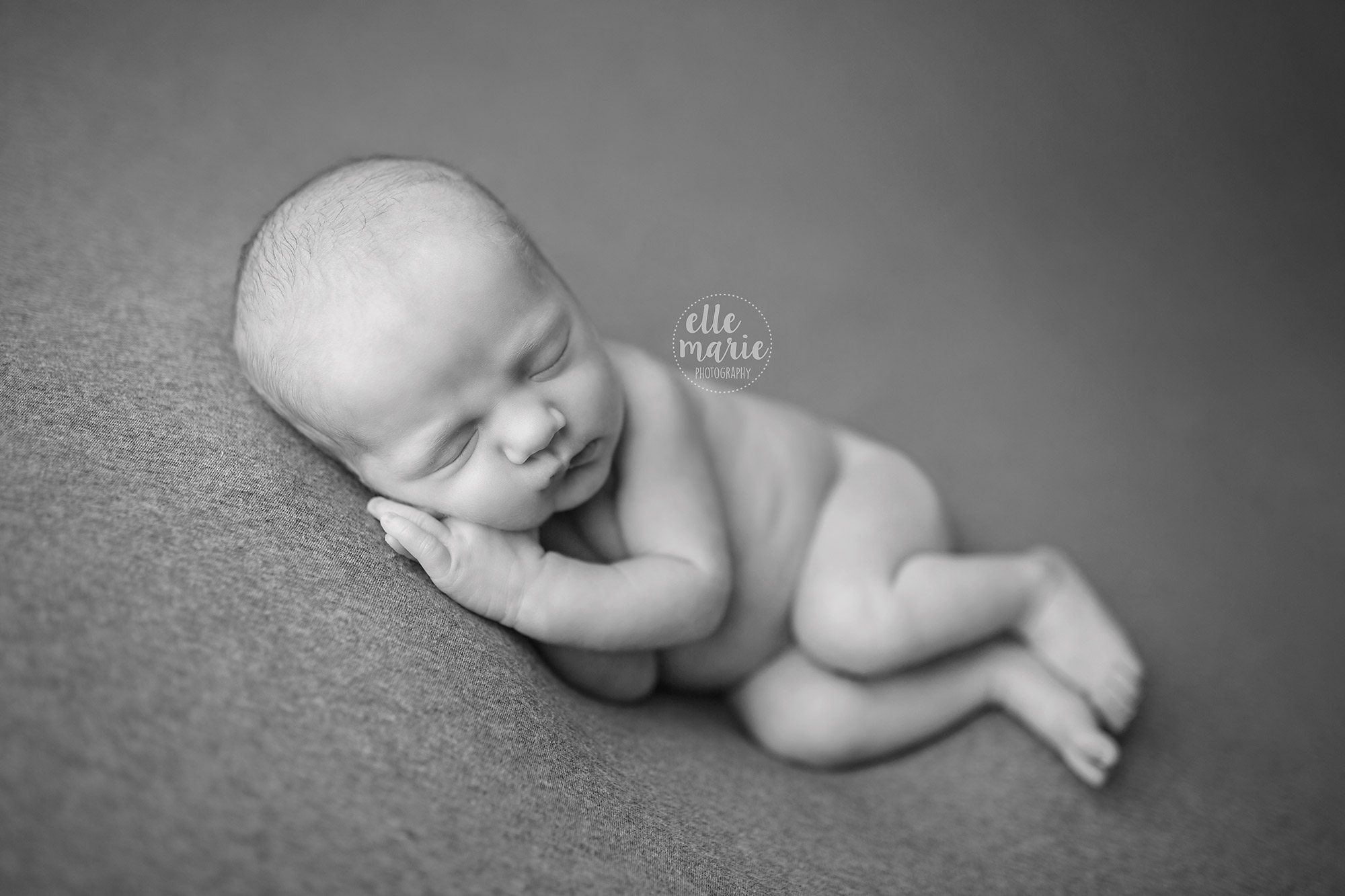newborn baby laying on side in black and white
