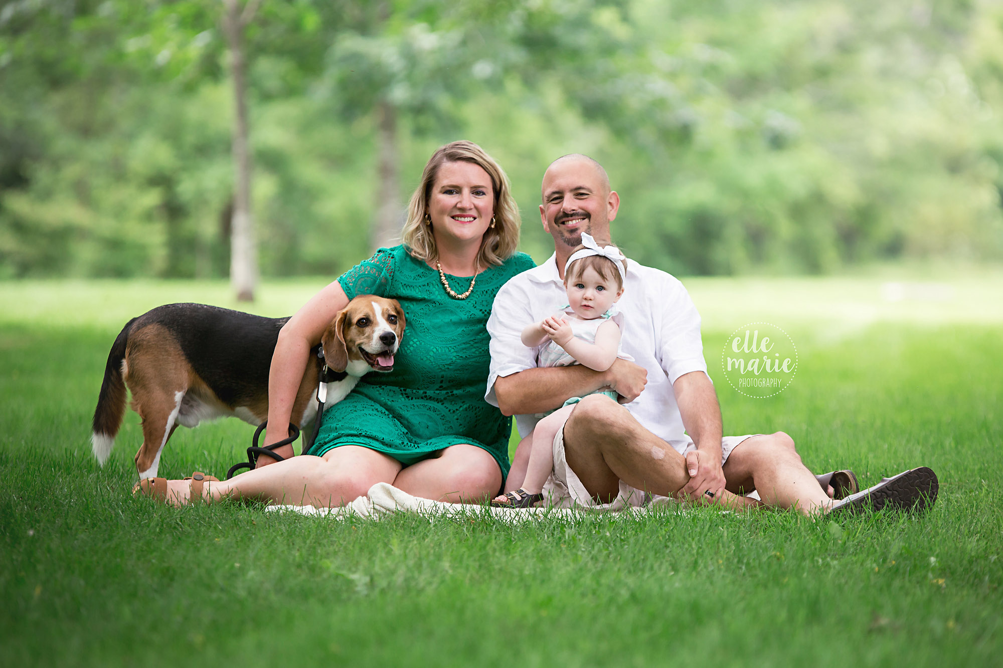 family sitting on grass with dog