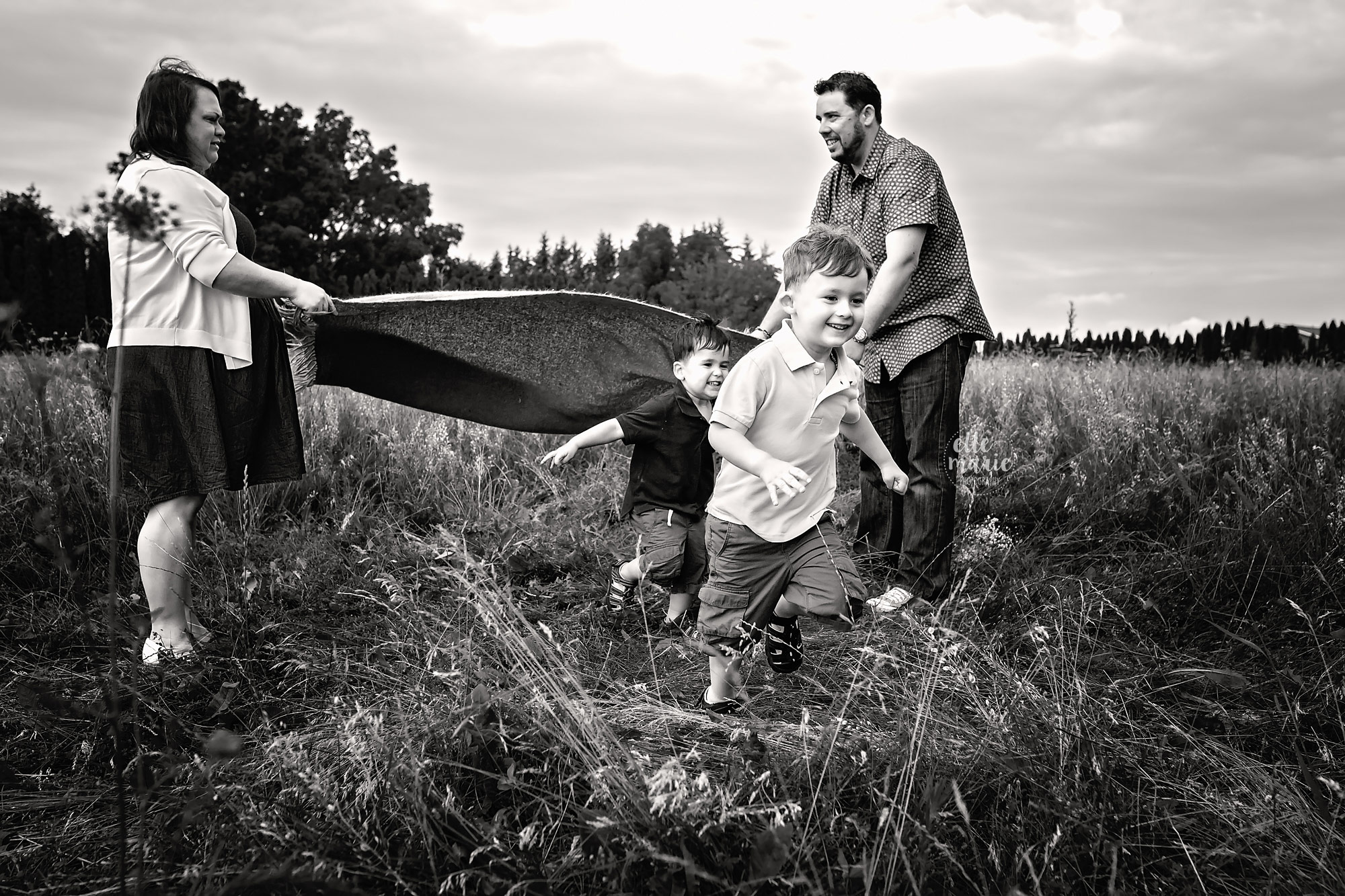 two sons running under a blanket their parents are holding