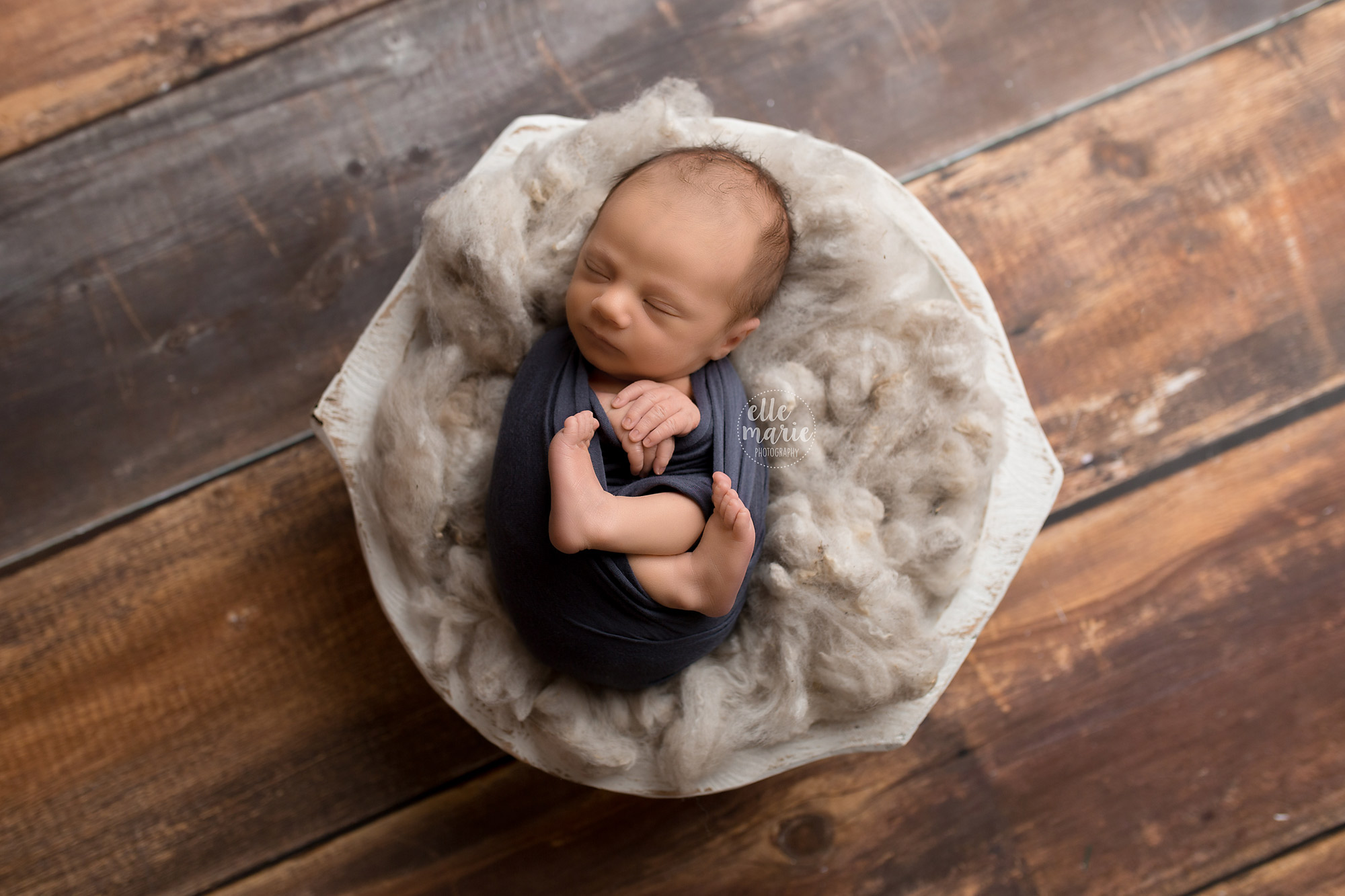 newborn boy wrapped in blue in bowl