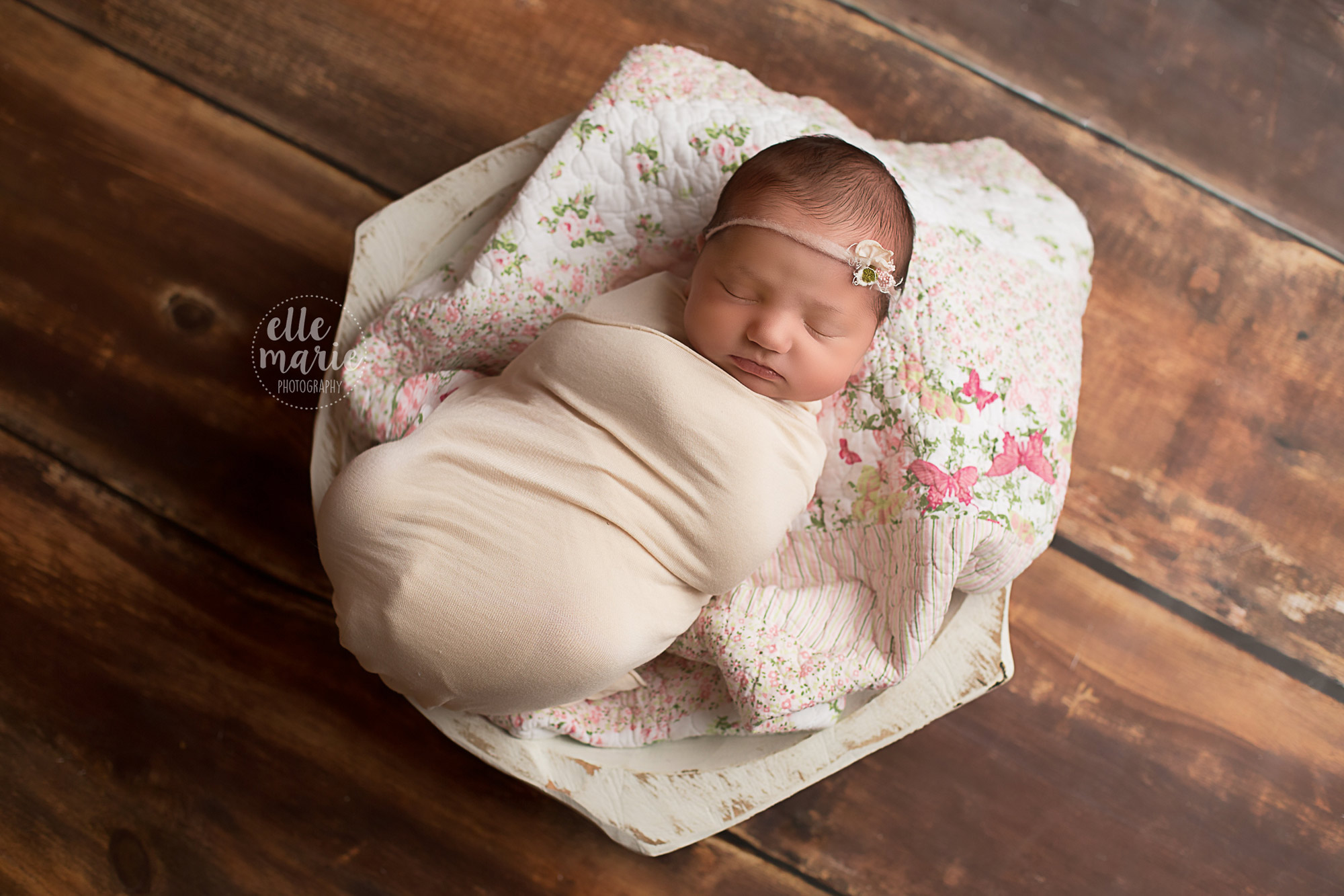 newborn girl in white bowl with pink quilt