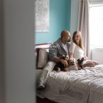 expecting couple on bed petting dogs