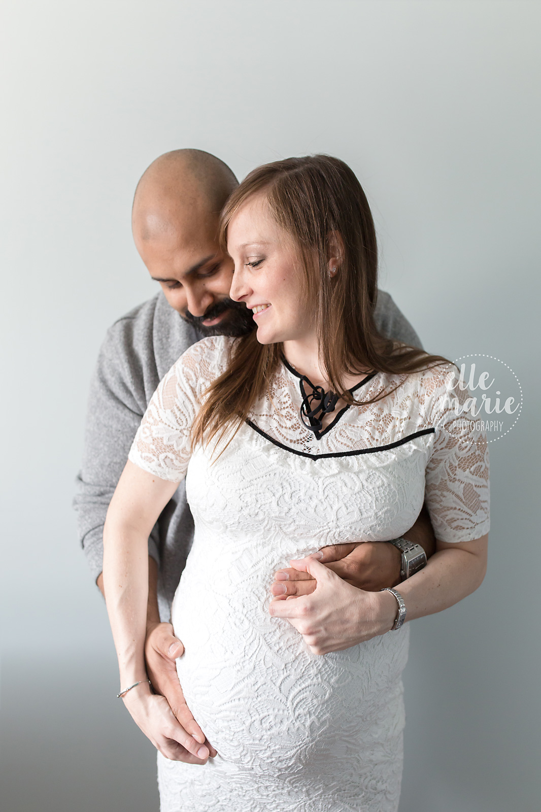 pregnant woman with husband hugging from behind
