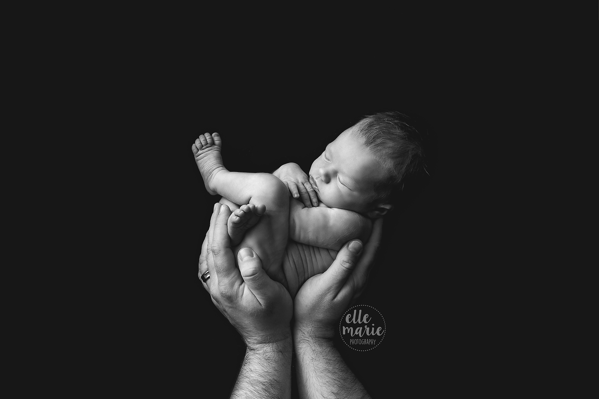 newborn baby girl in daddys hands in black and white