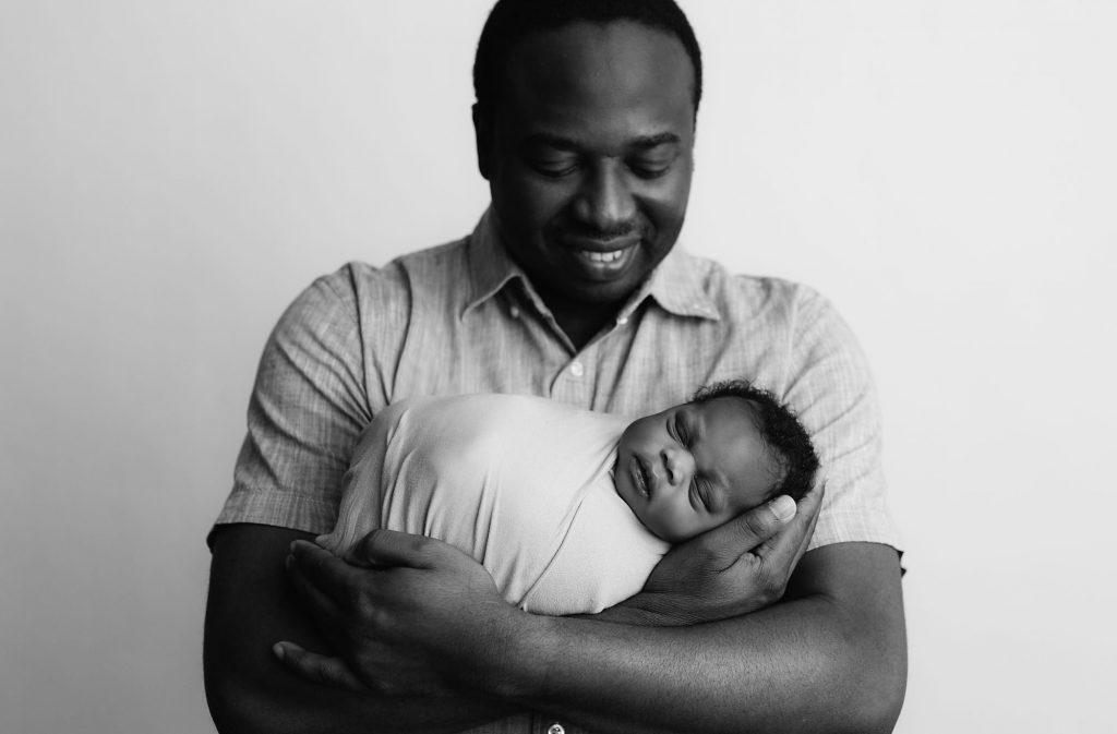 proud dad holds newborn in arms