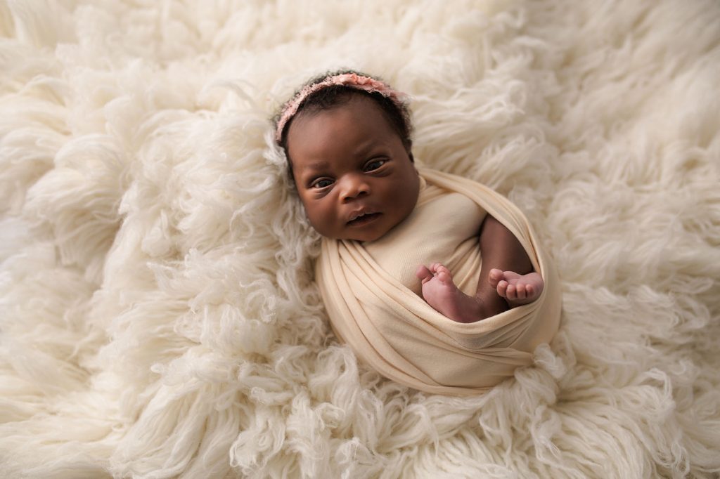 newborn baby girl wrapped in cream