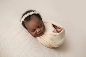 newborn baby girl wrapped in cream with matching headband