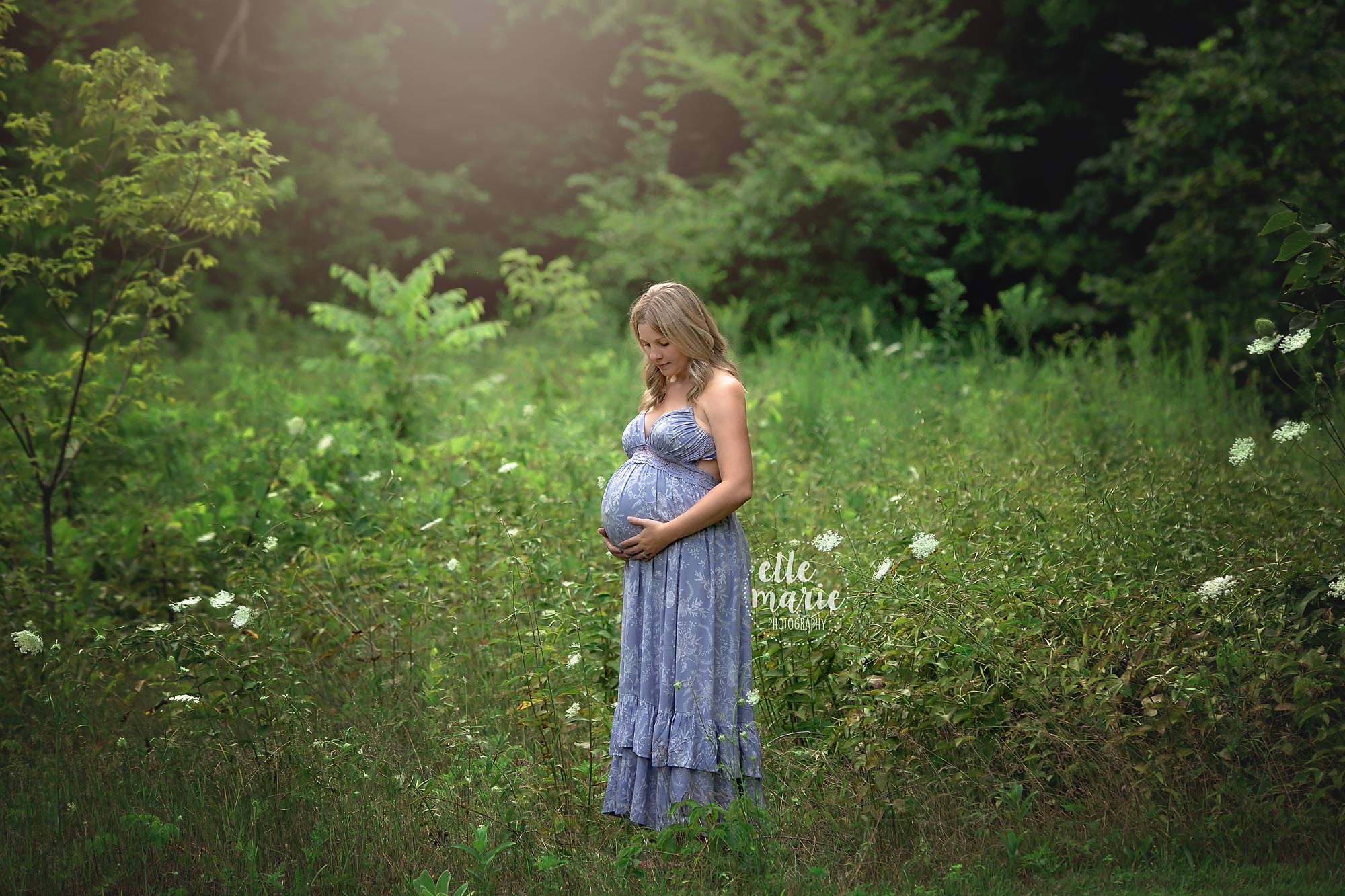 pregnant mom looking at belly in meadow