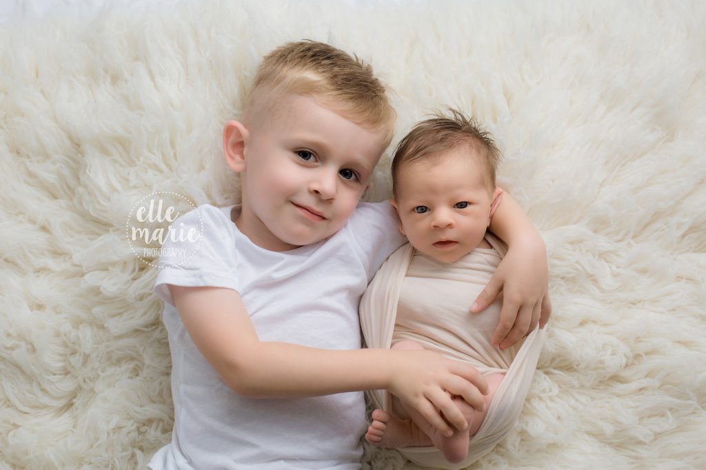 Preschool brother holding newborn sister