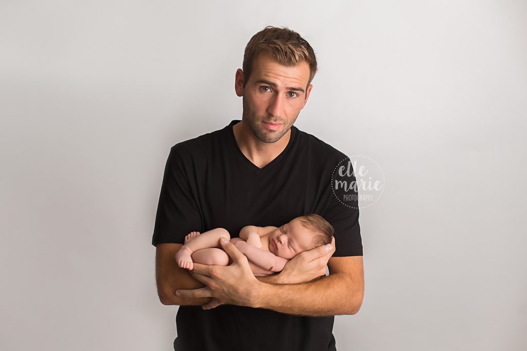 dad holds newborn baby girl in his arms