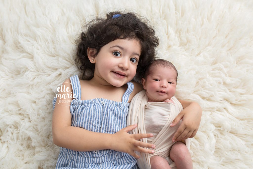 newborn baby and sister snuggling