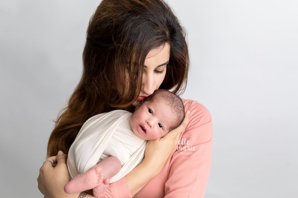 newborn baby girl in moms arms while snuggling her