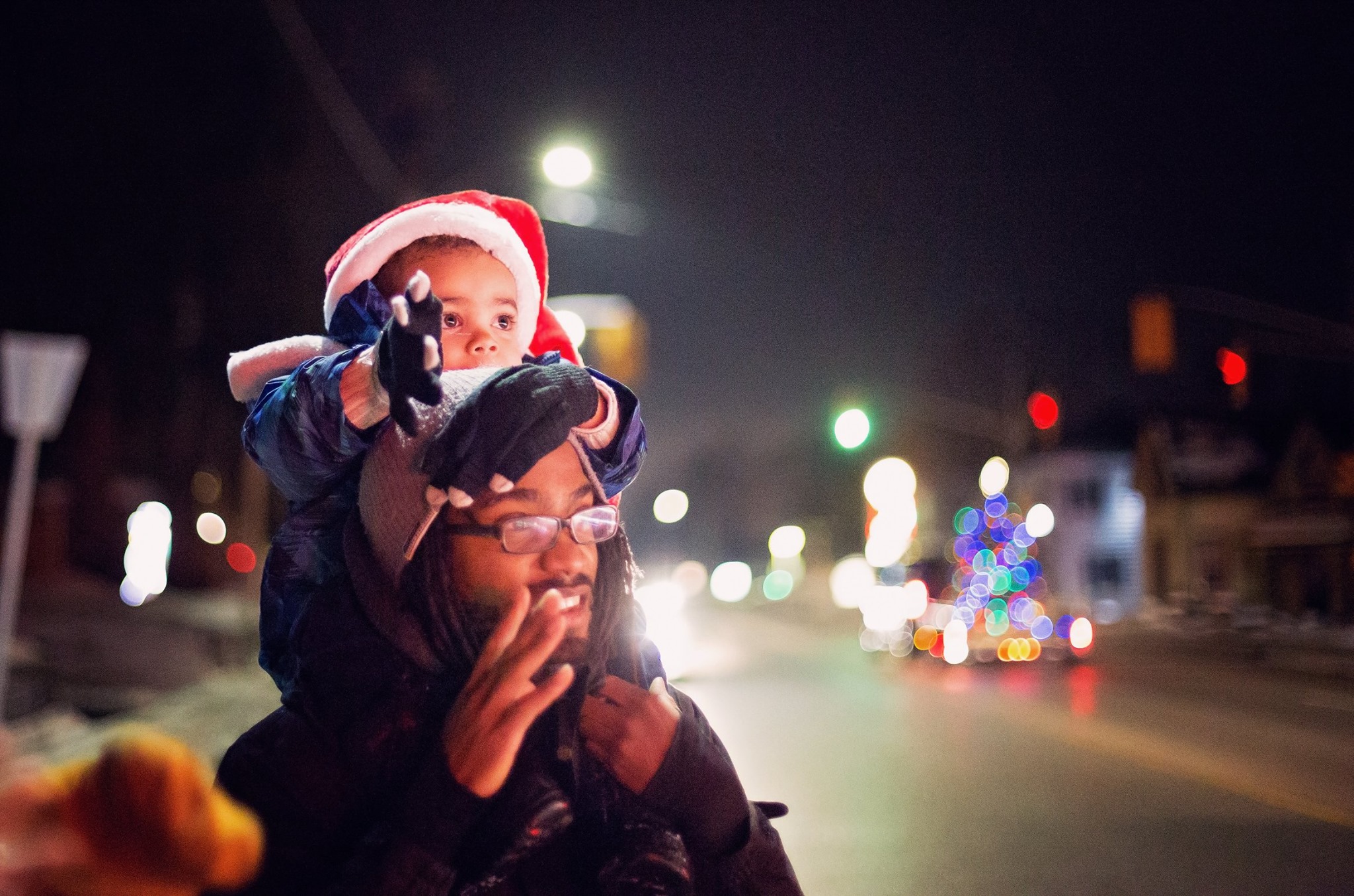 son on dad's shoulders watching Christmas Parade