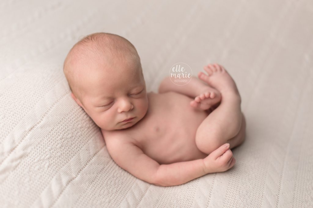 newborn baby boy laying on back with legs curled up