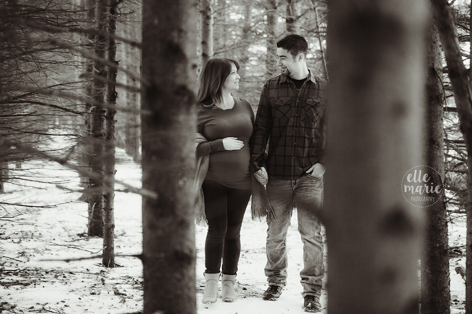 expecting couple walking in the forest in winter