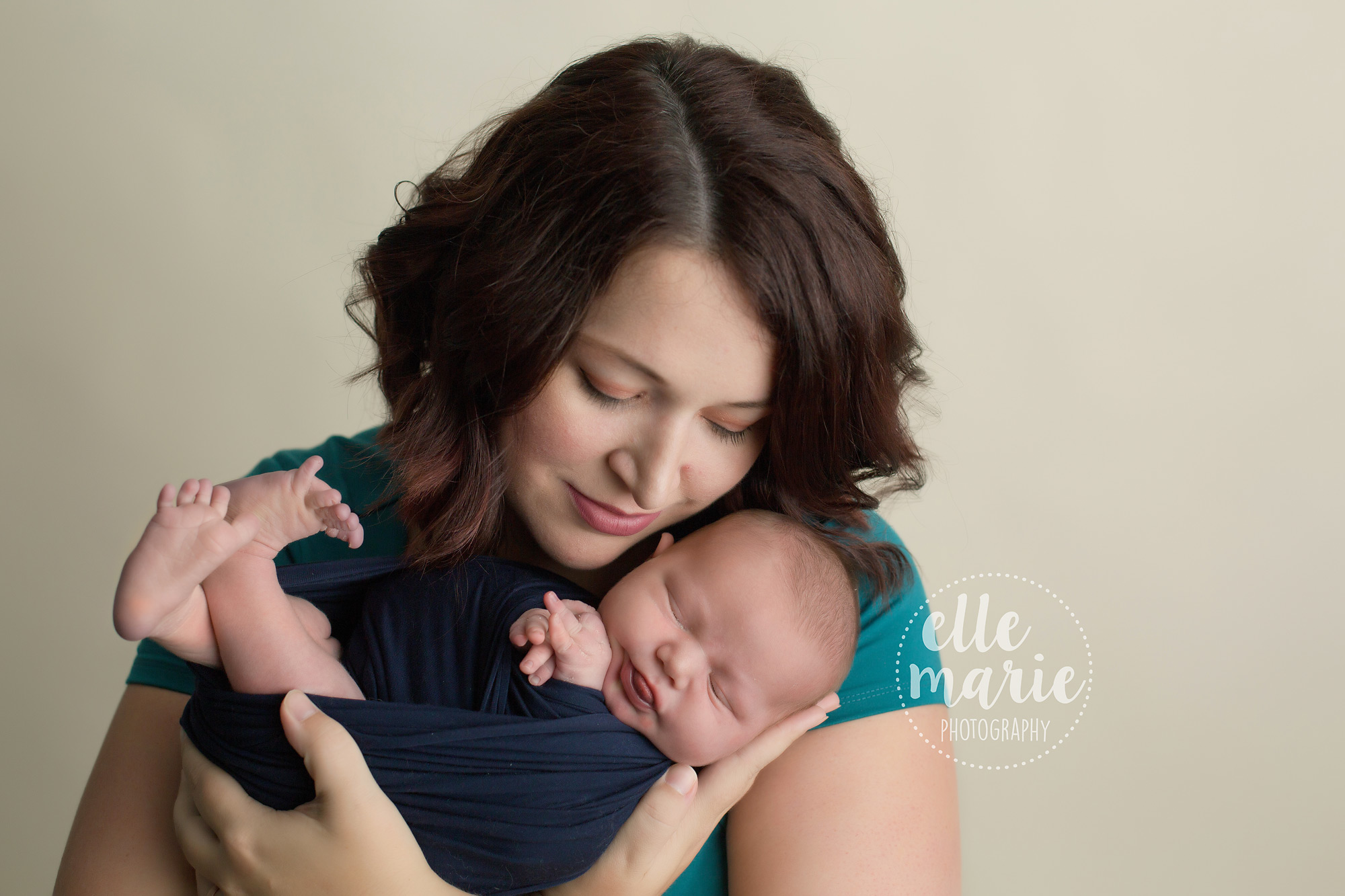 mom of 3 boys poses with newborn baby wrapped in navy