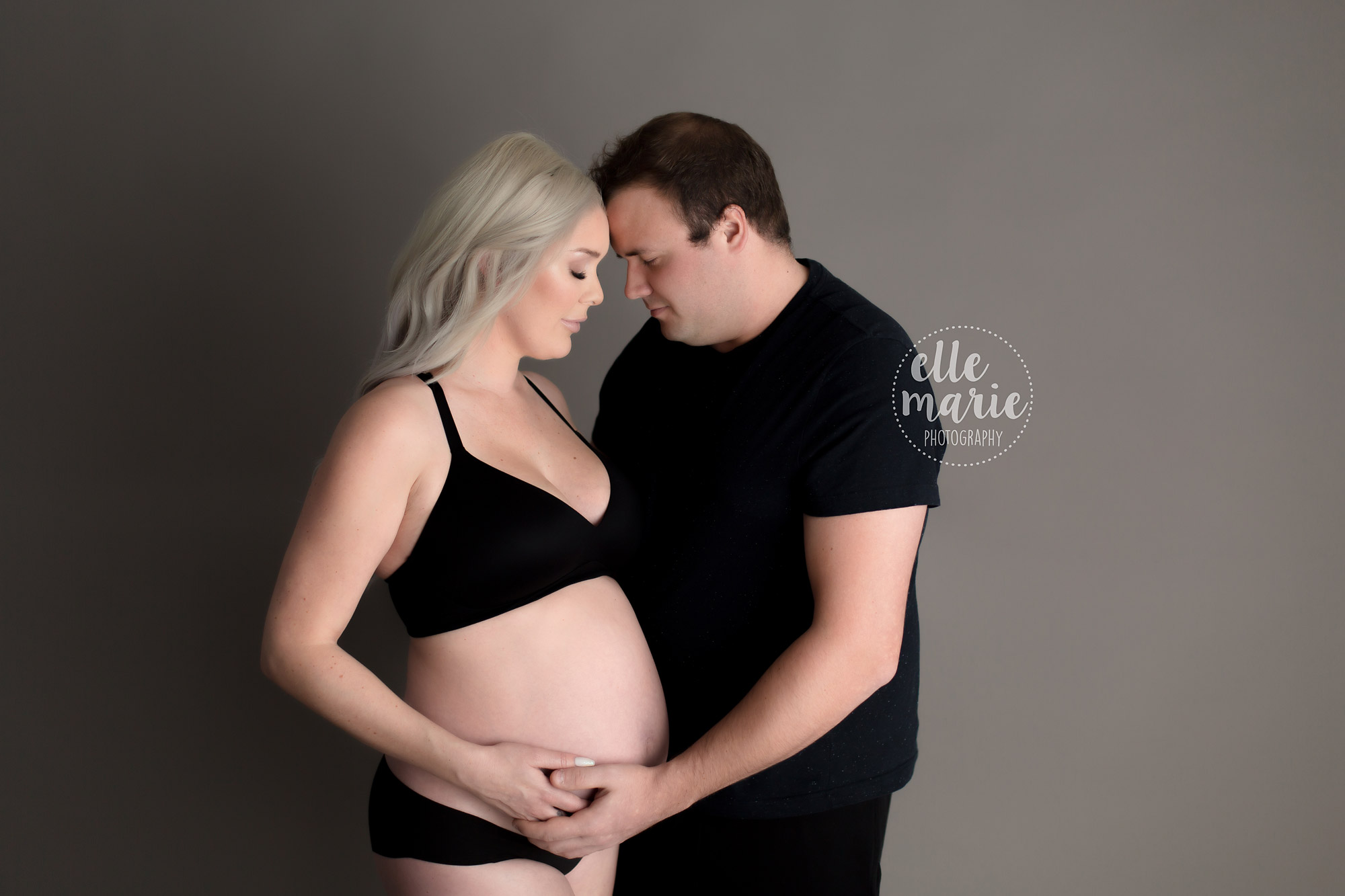 pregnant lady with bare belly hugging partner
