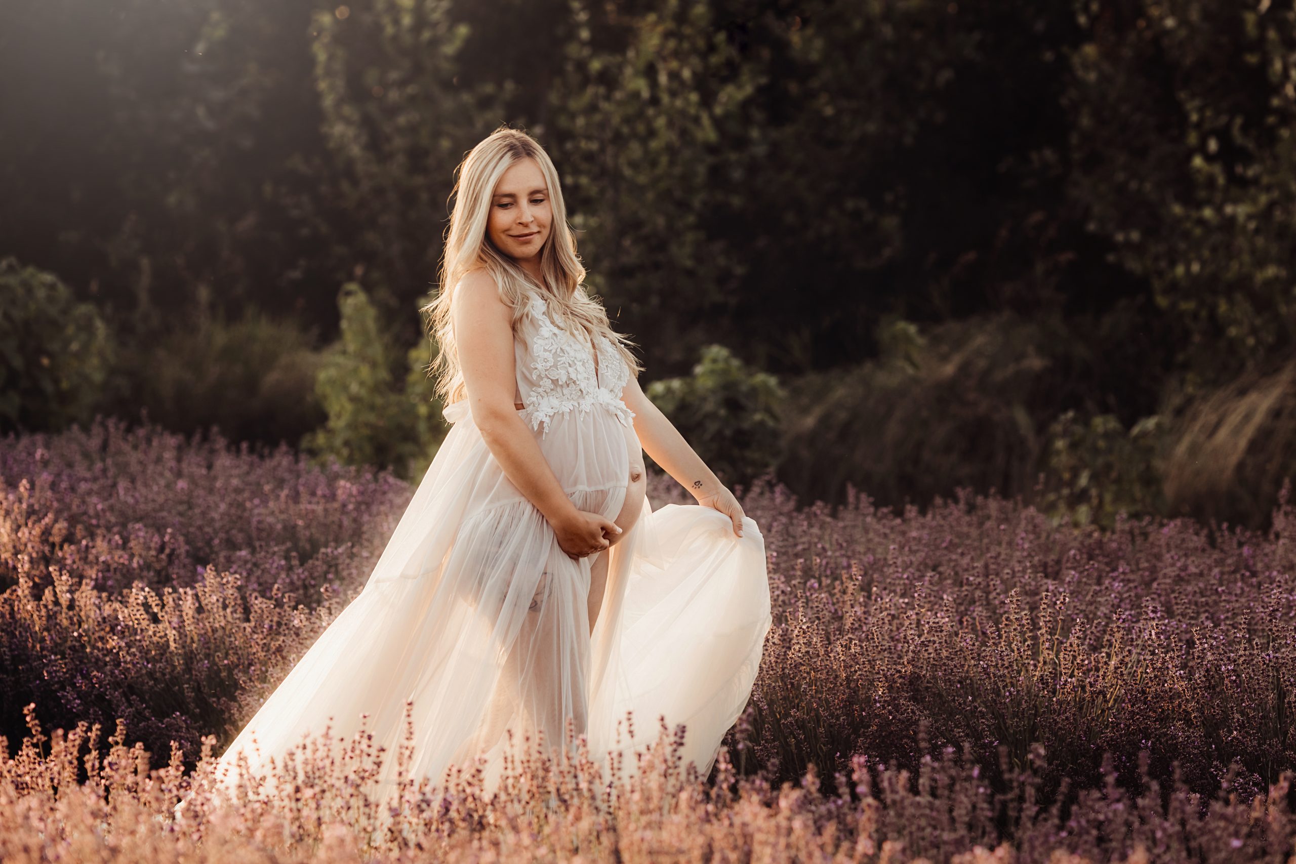 woman walking through lavender with pregnant belly