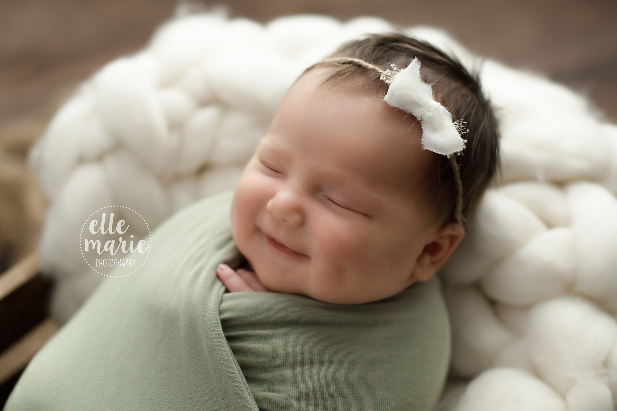 smiling newborn baby girl wrapped in green