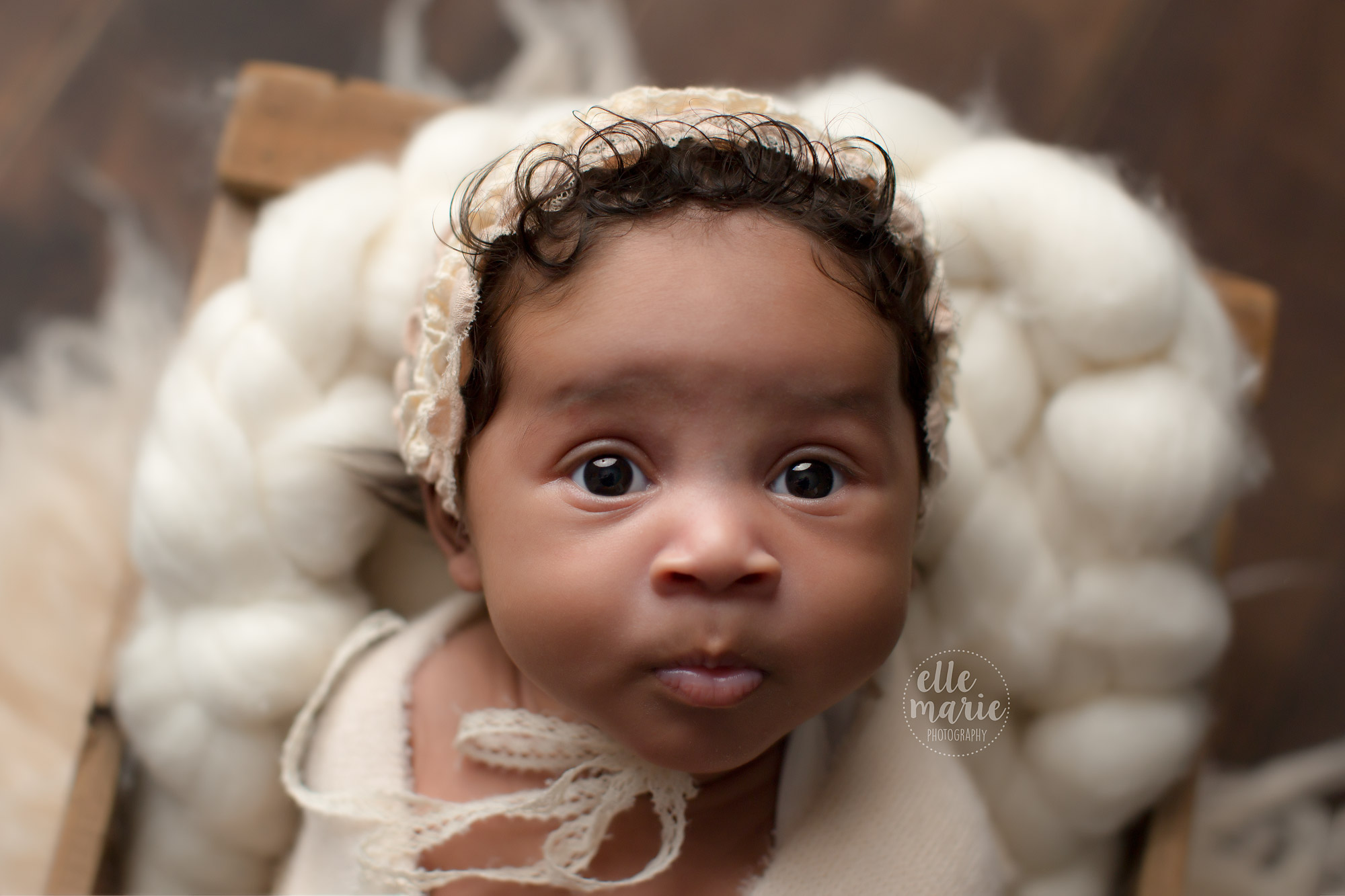 newborn baby girl in bonnet with wide bright eyes
