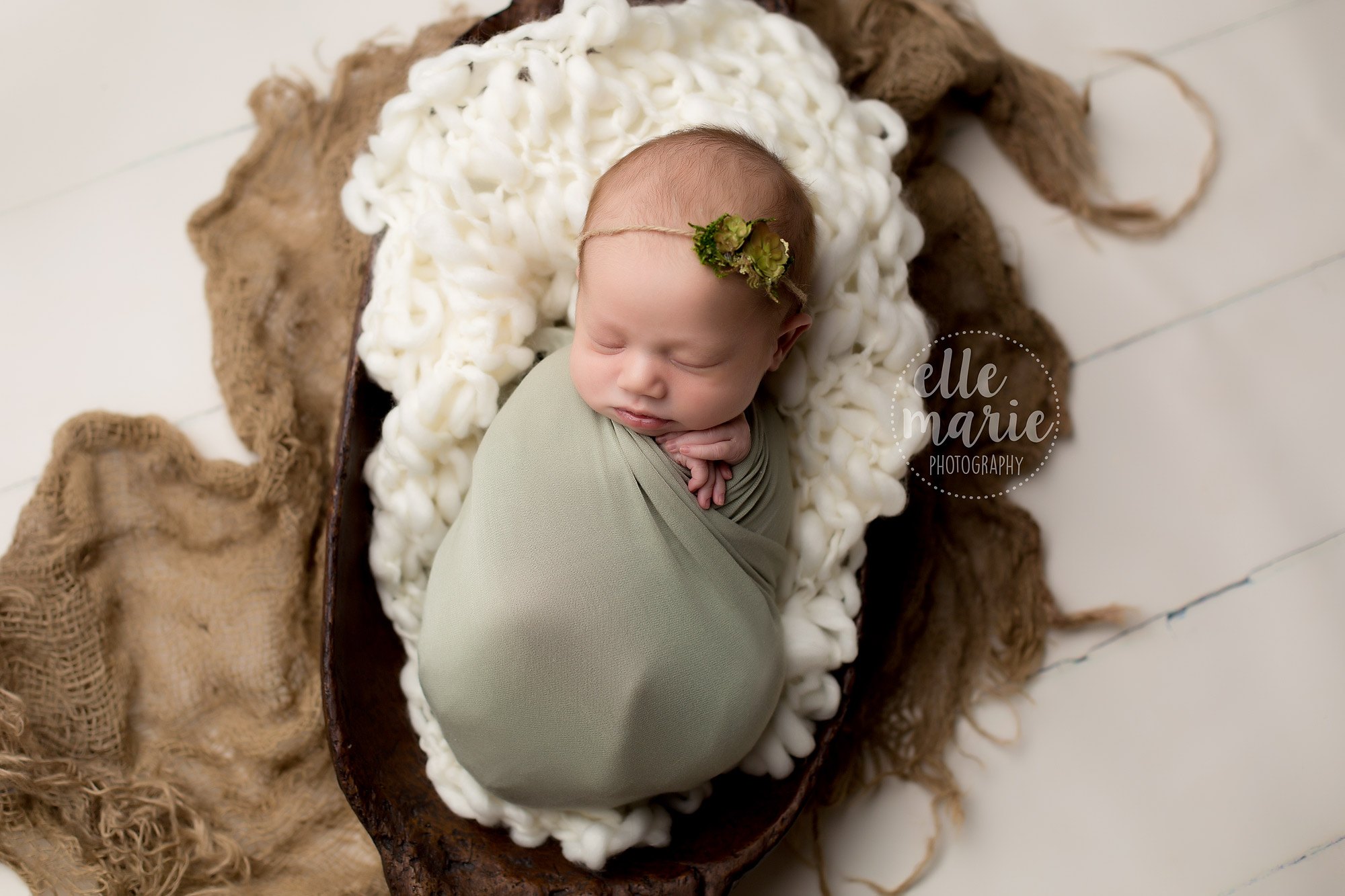 newborn baby girl wrapped in green with succulence headband