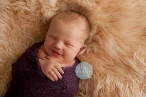 smiling newborn in purple wrap