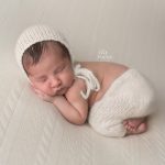 newborn baby dressed in cream with bonnet