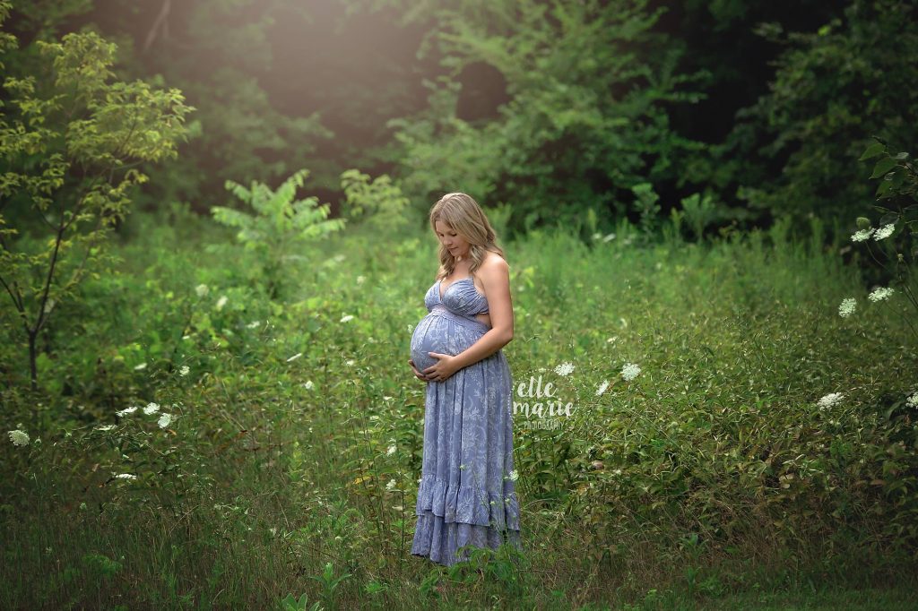 pregnant mom looking at belly in meadow