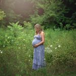 pregnant mom looking at belly in meadow