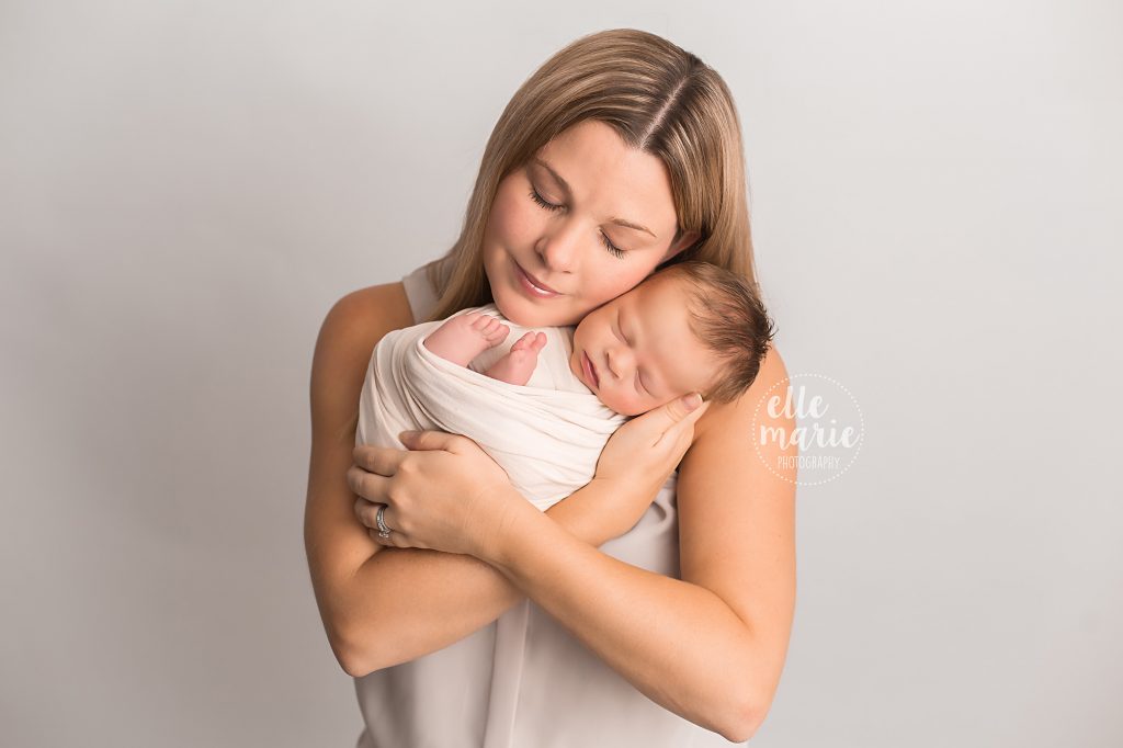 mom holds newborn baby girl in her arms with eyes closed