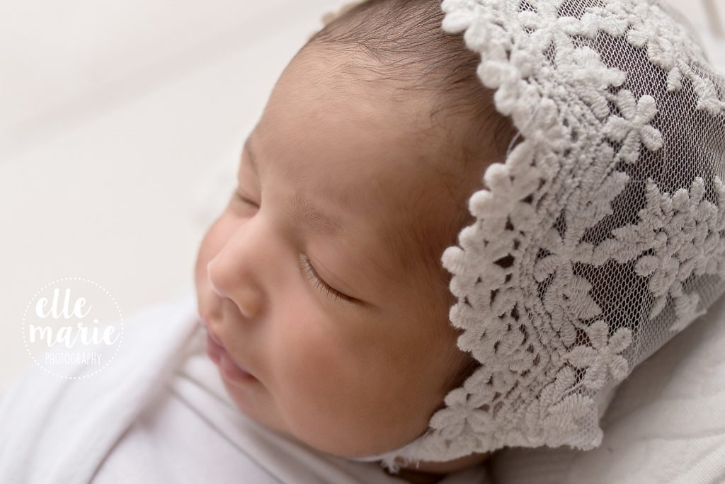 newborn baby girl in white lace bonnet
