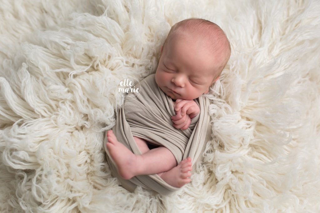 newborn baby boy wrapped in cream