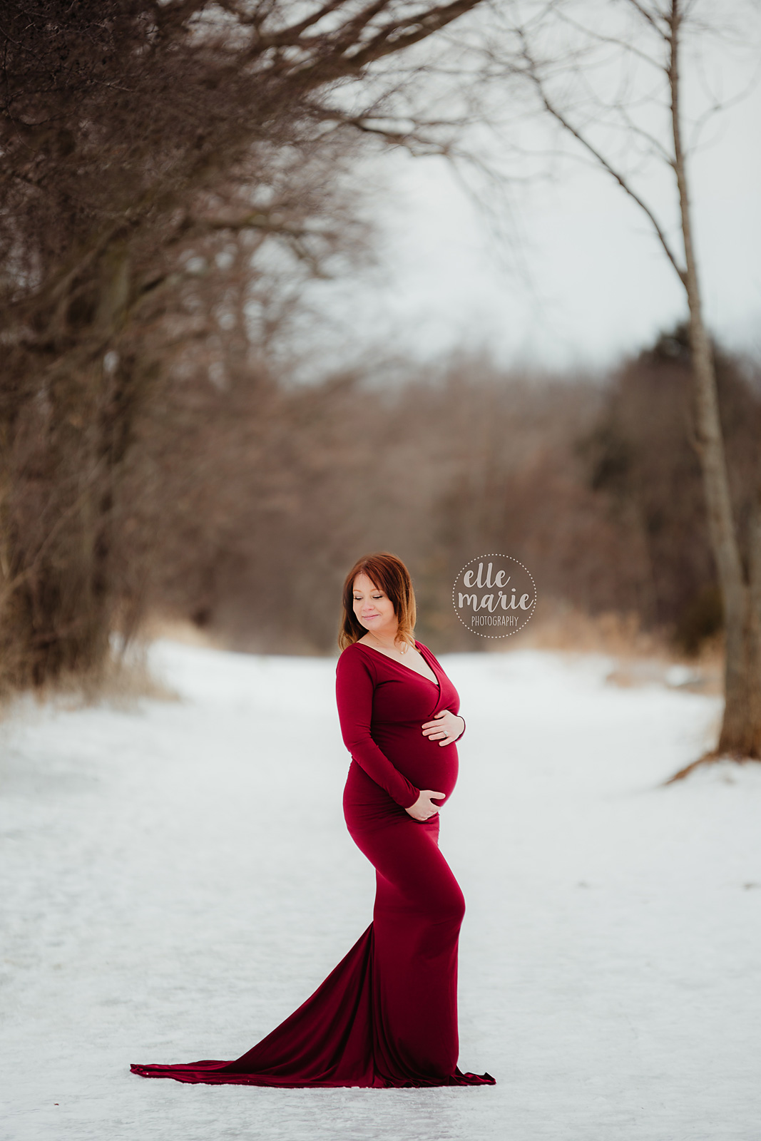 expecting mother in red gown in winter setting looking over shoulder