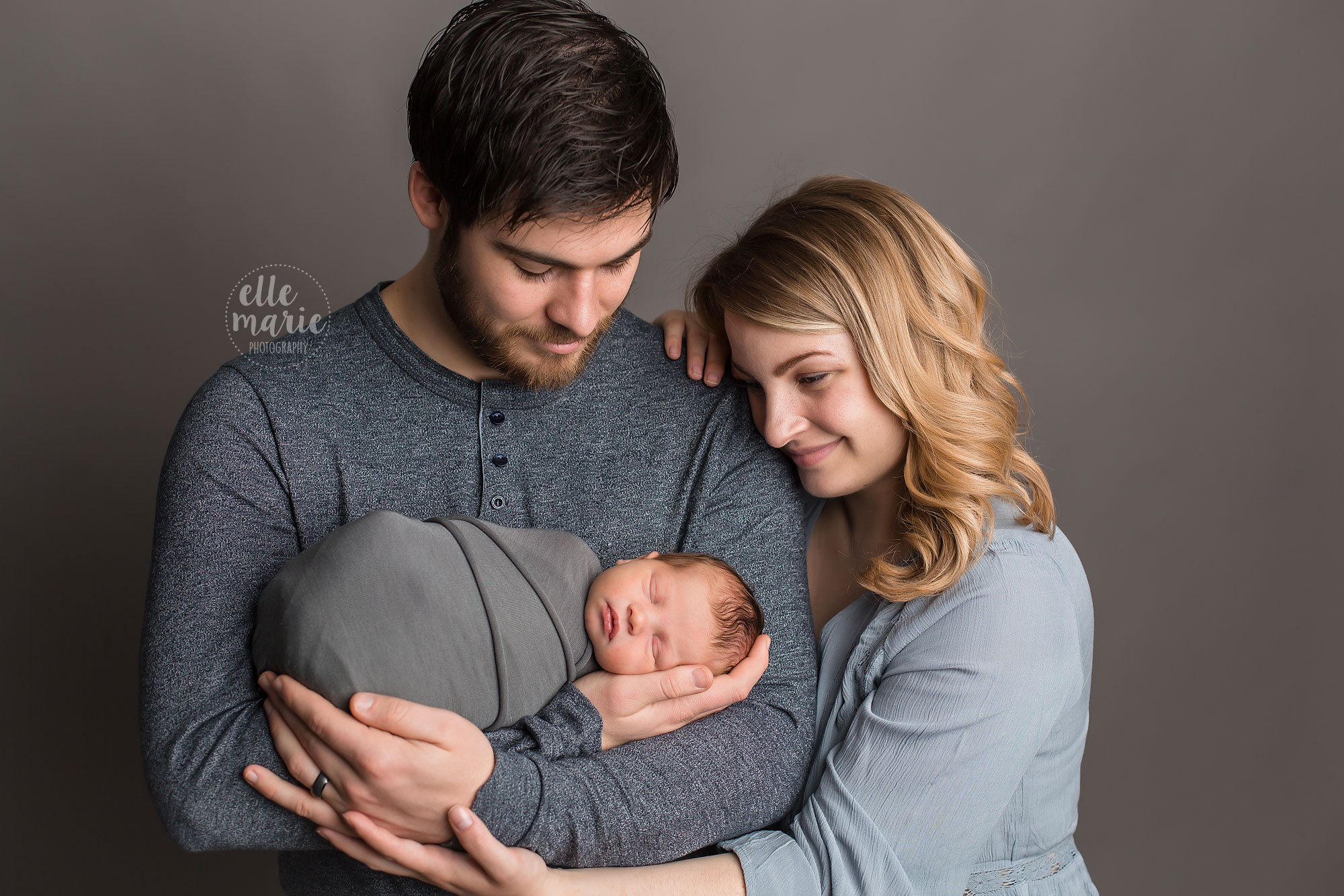 family of 3 with dad holding newborn baby boy