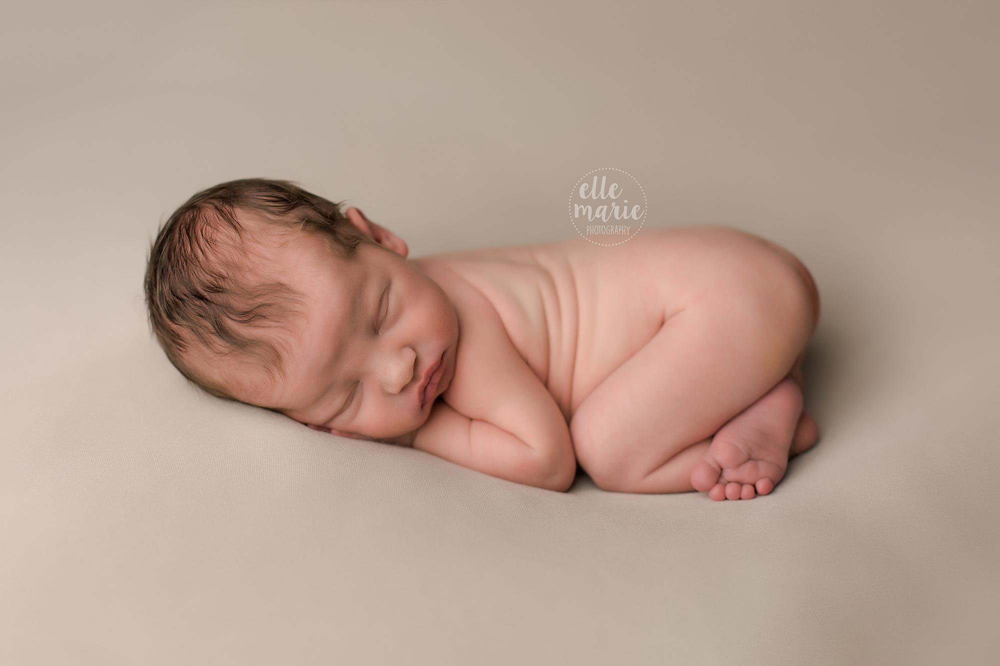 newborn boy laying on tummy on beige