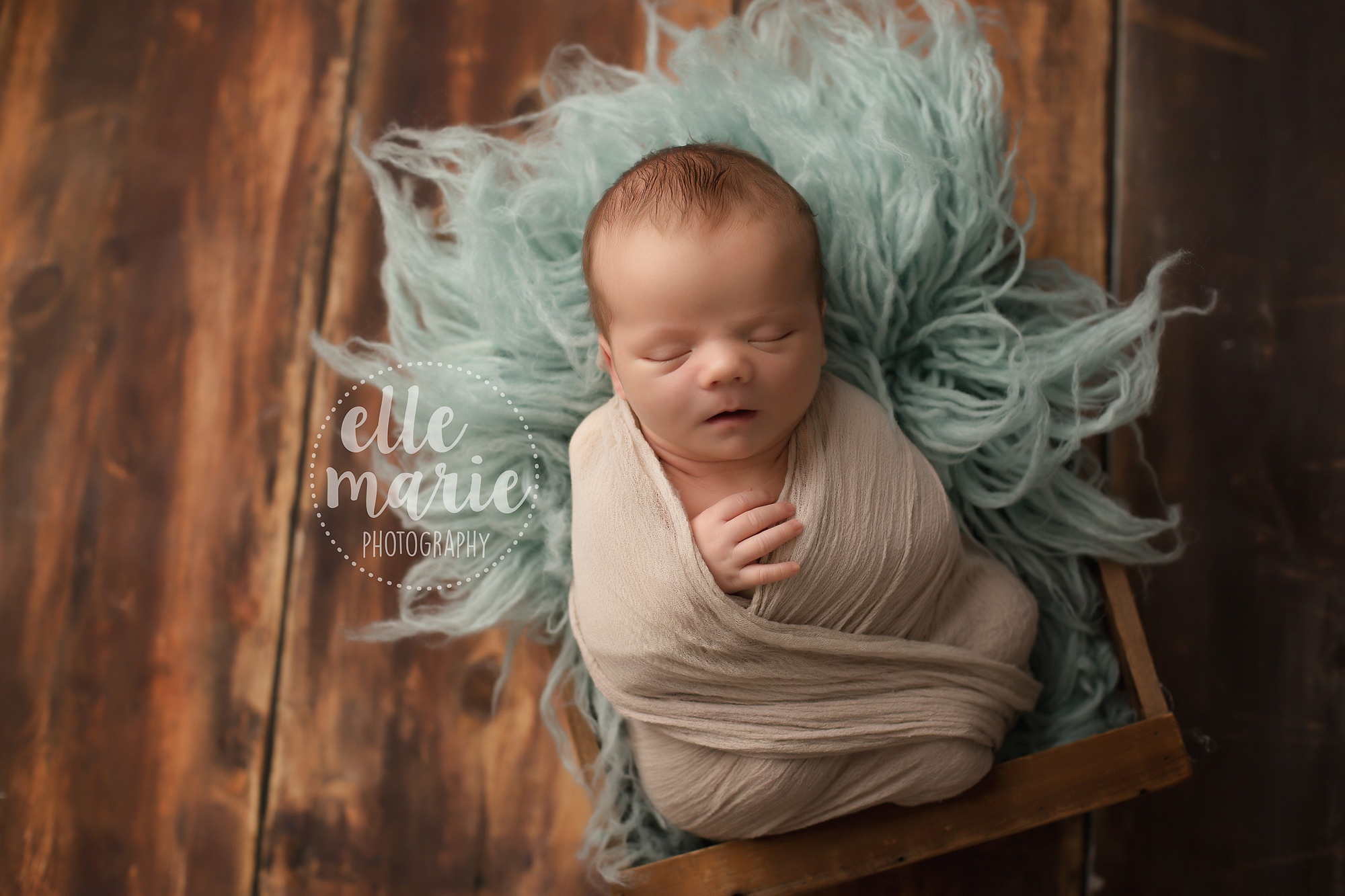 Newborn baby boy on blue fur and wood