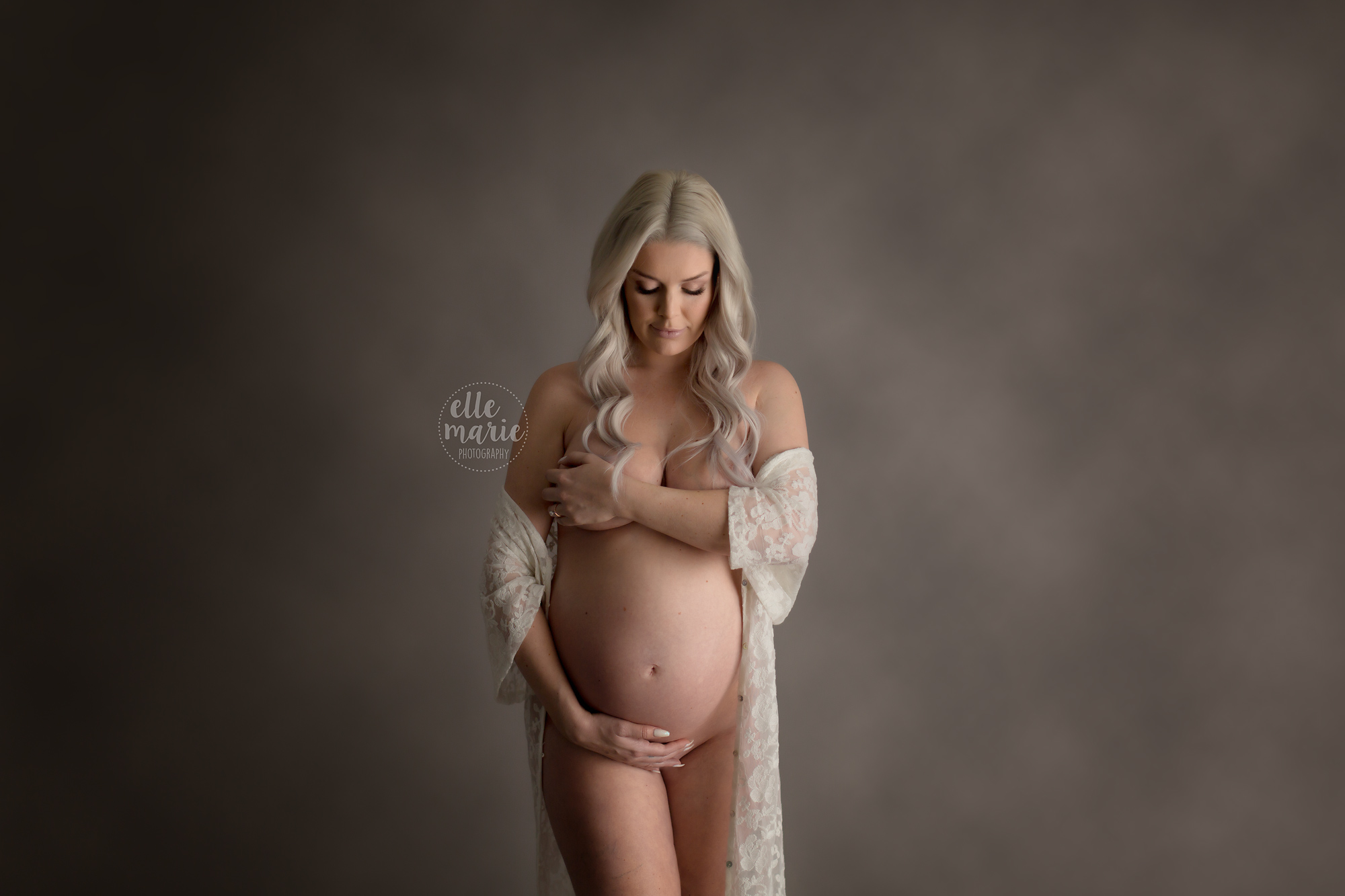 pregnant mother holding bare belly with lace gown draped around her