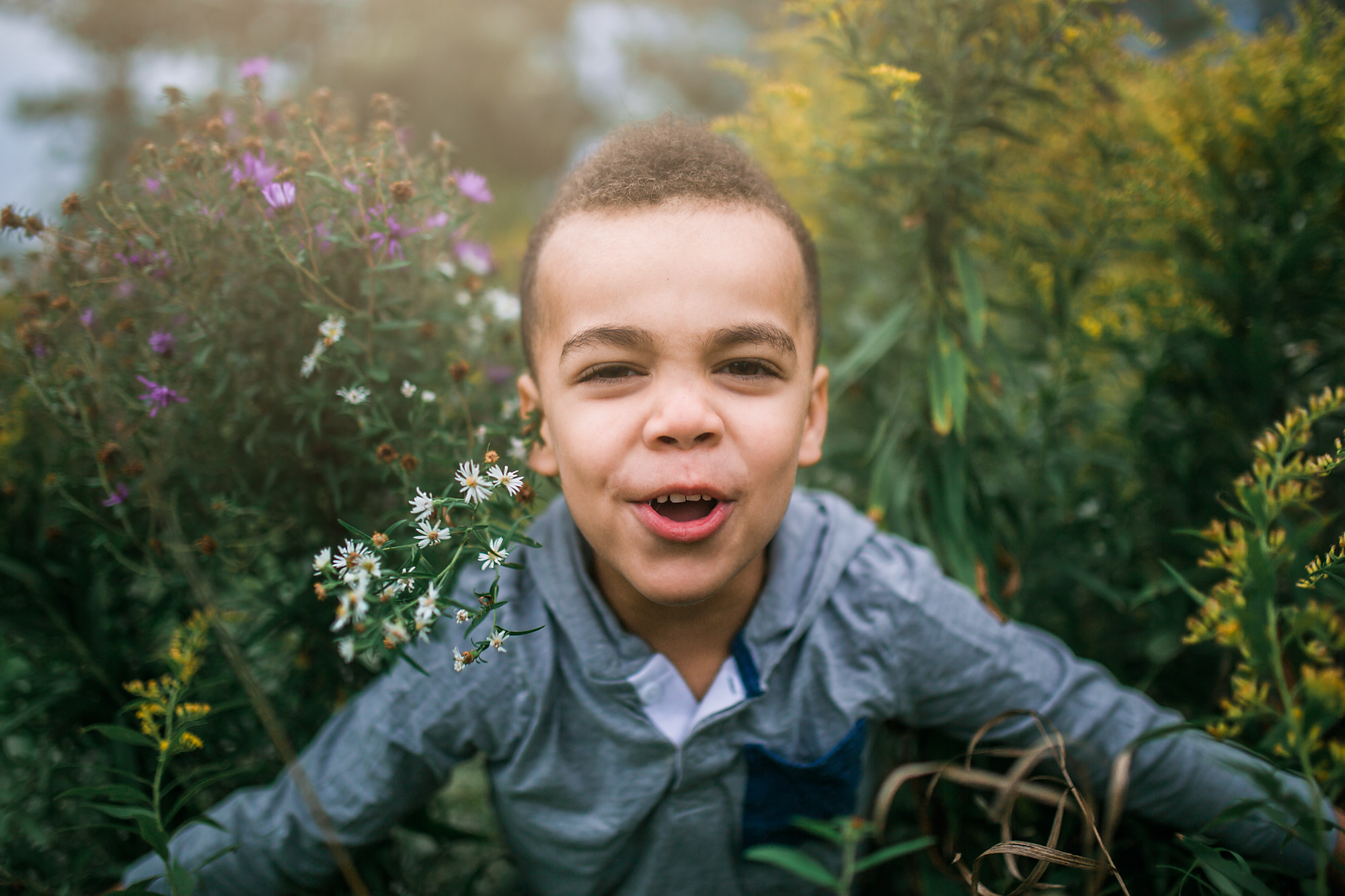 young boy bursts through the weeds