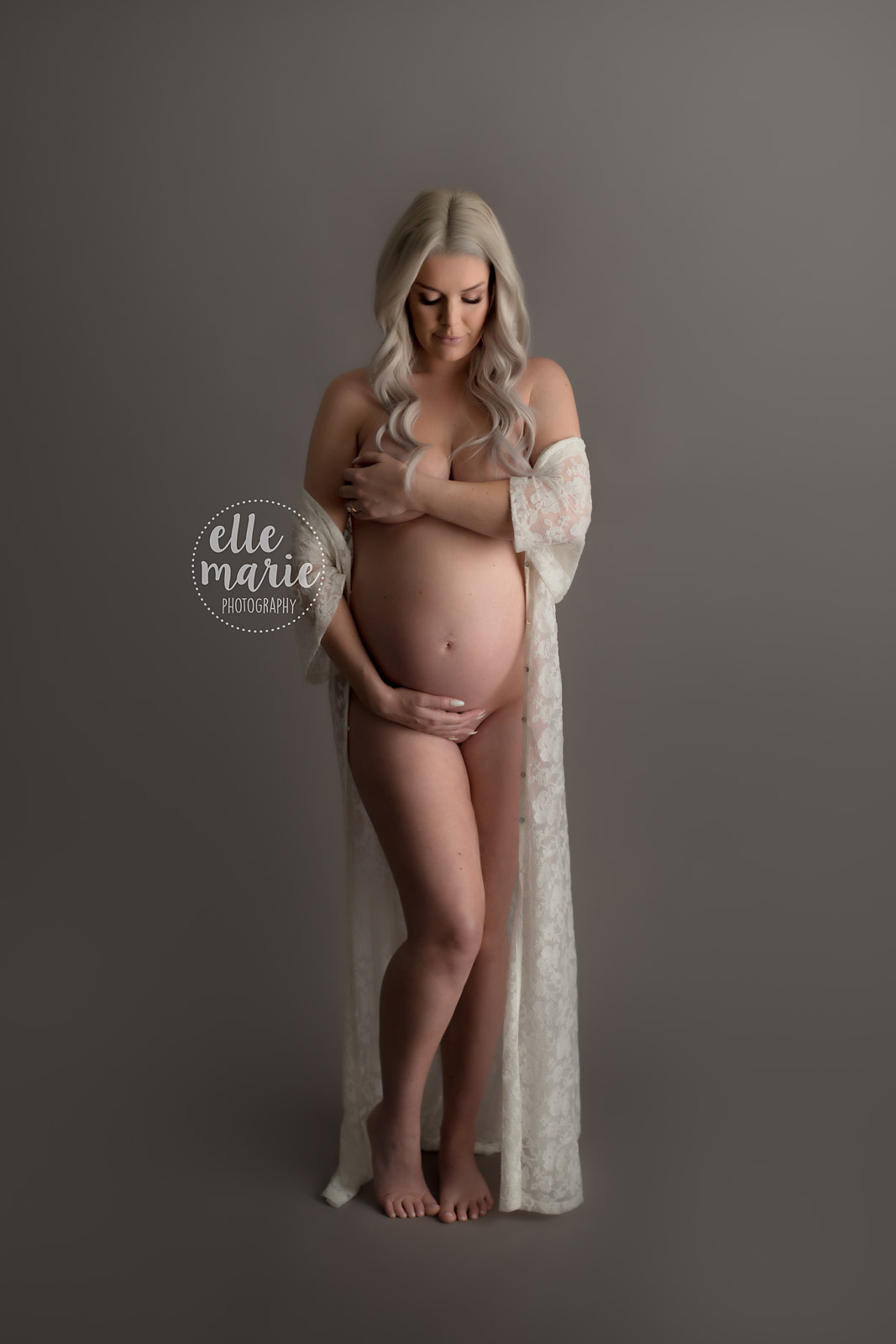 pregnant lady poses nude while hugging her belly