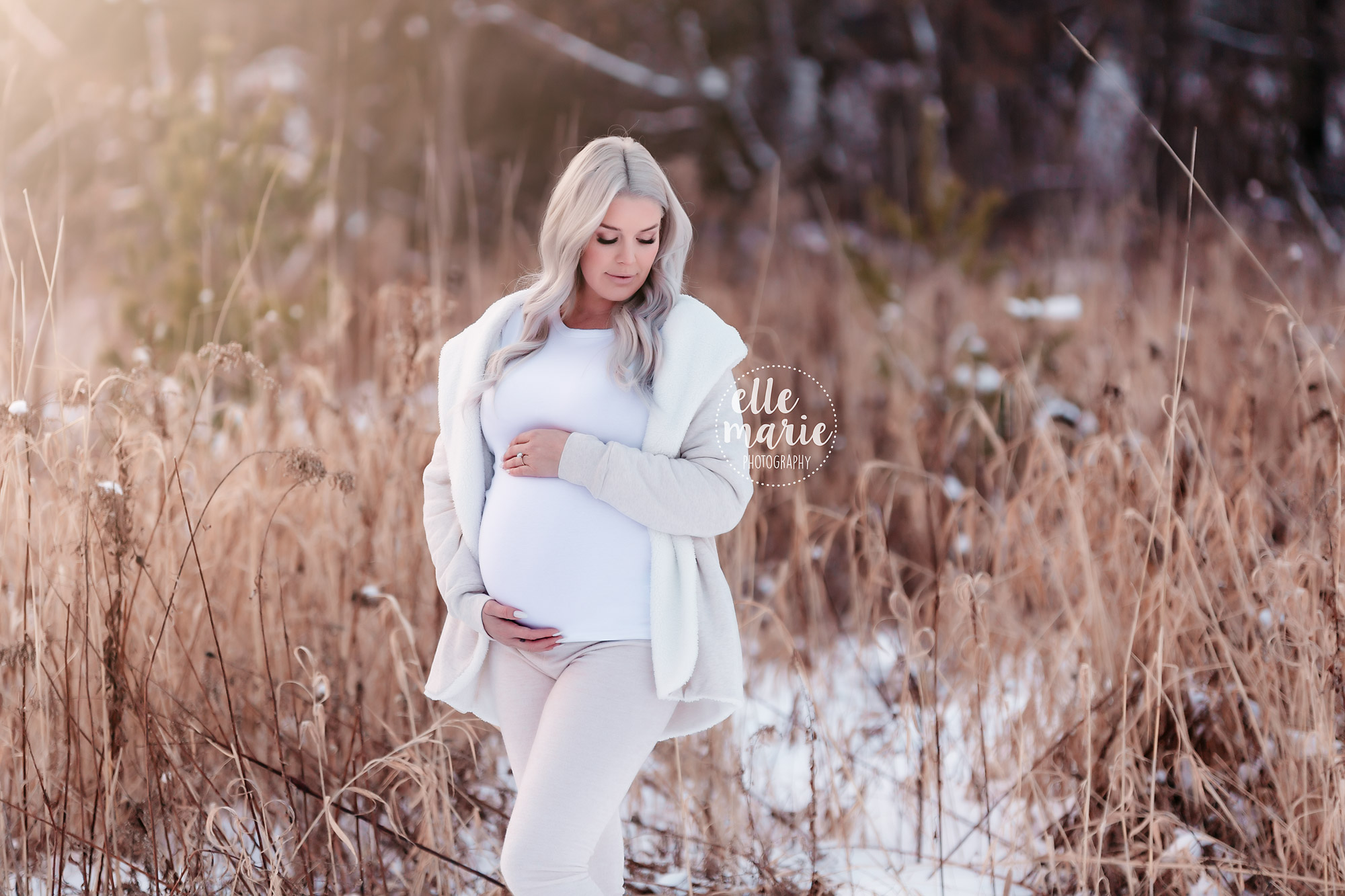 pregnant lady outdoors in the snow hugs belly