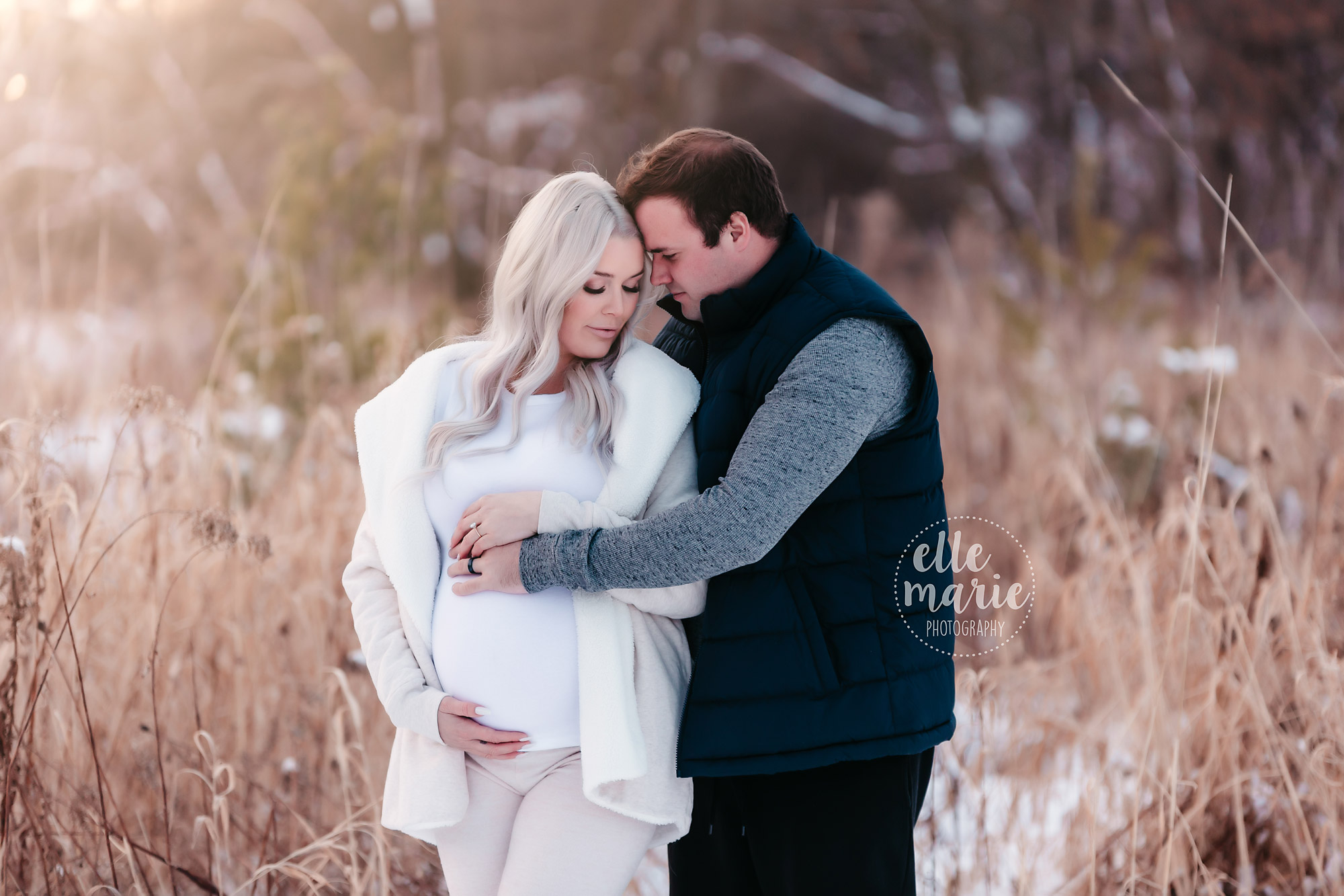 expecting couple embraces in the snow