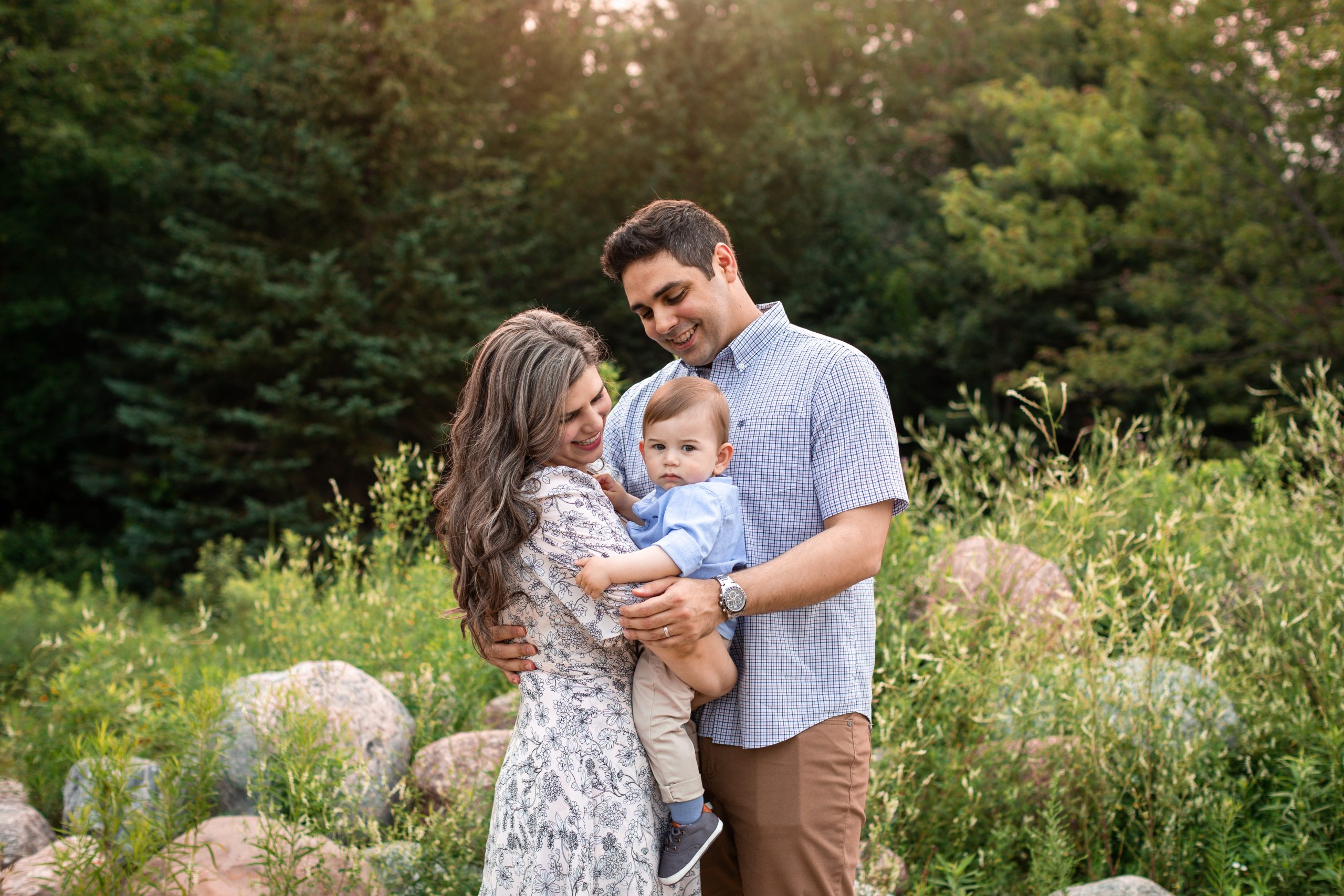 Family of 3 snuggling baby boy outside