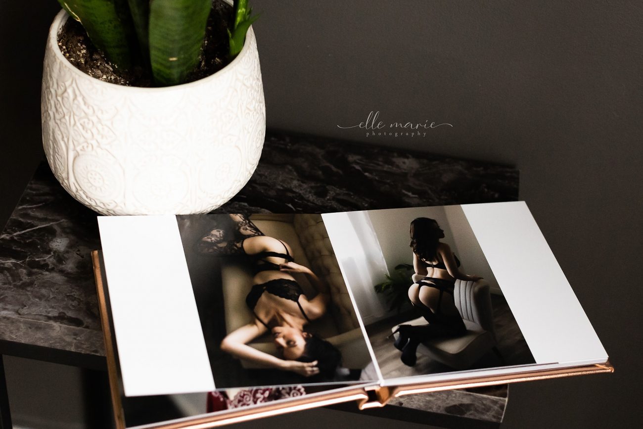gold cover boudoir album sitting open on a table with a plant beside it.