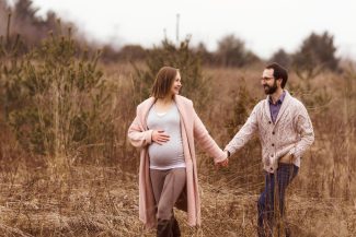 pregnant couple walking through a nature path