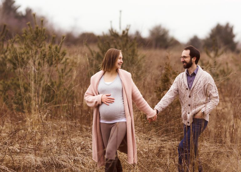 pregnant couple walking through a nature path