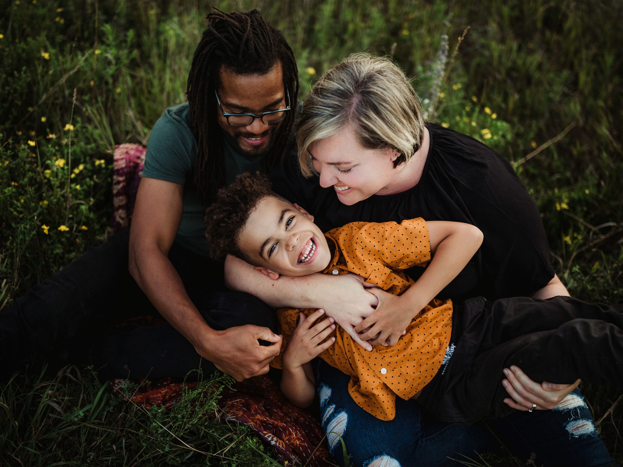 husband and wife tickling their son for a family photo