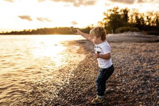 young boy throwing rocks into the lake